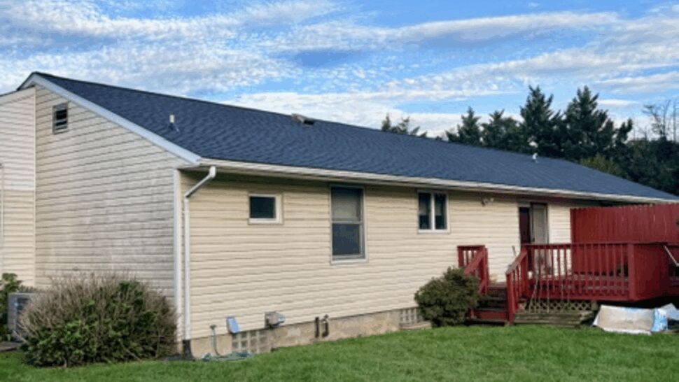Rear Home Roofing View | Atlas Exteriors Rear view of a single-story home with a dark shingle roof and beige siding.