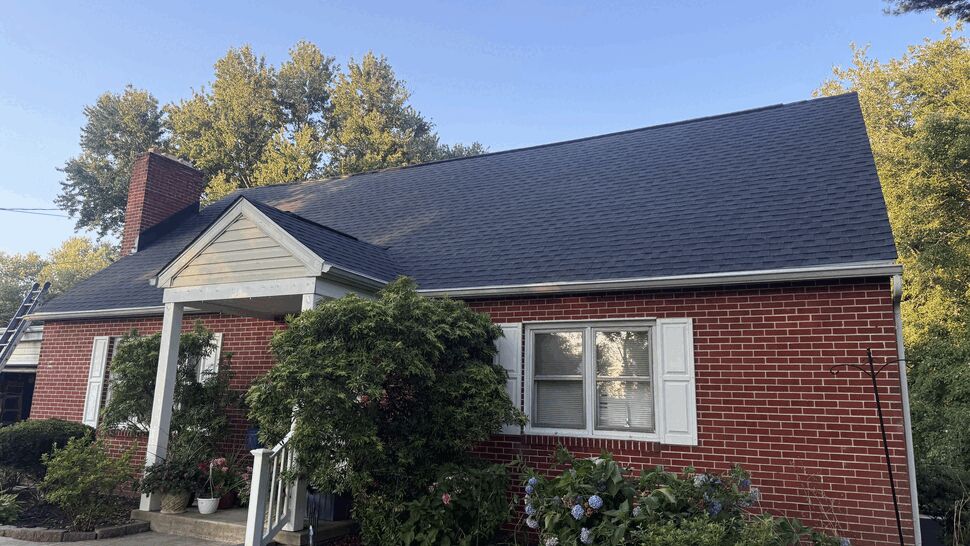 Brick home with new shingle roof | Atlas Exteriors Brick house with dark shingle roof and front porch.