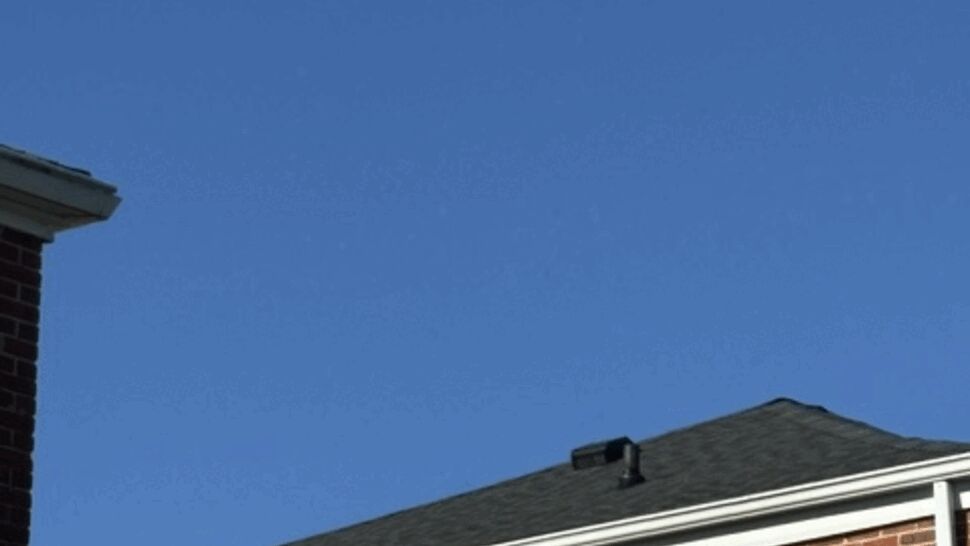 Brick Home Roof Detail | Atlas Exteriors Close view of a gray shingle roof, brick wall, chimney, and white trim.