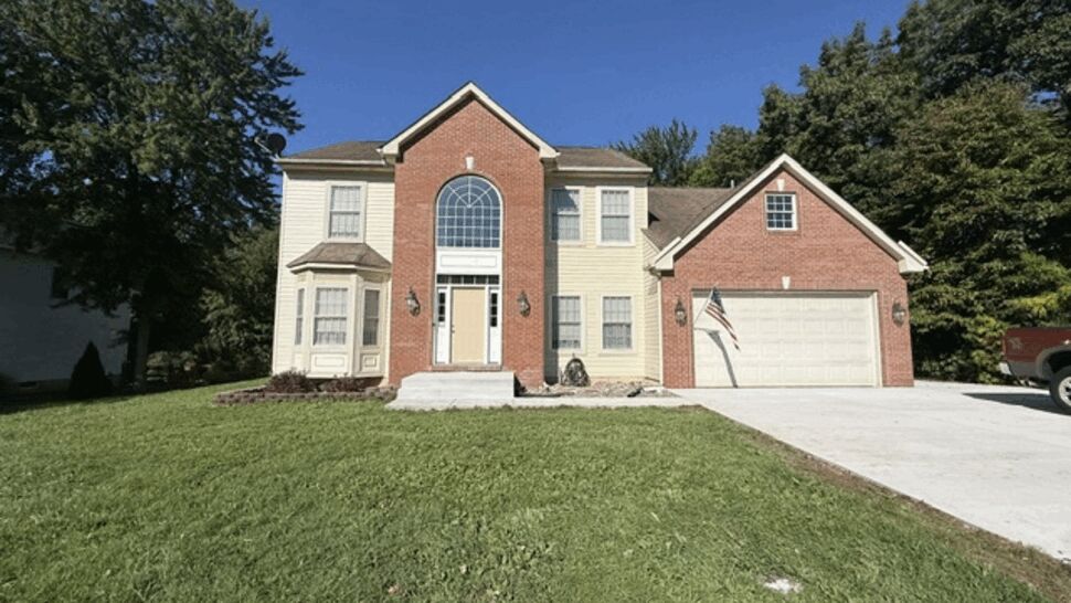 Two-story colonial home front facade with brick entry and light yellow siding