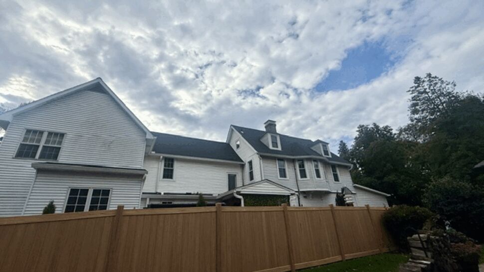Rear view of a white home with a newly finished dark roof