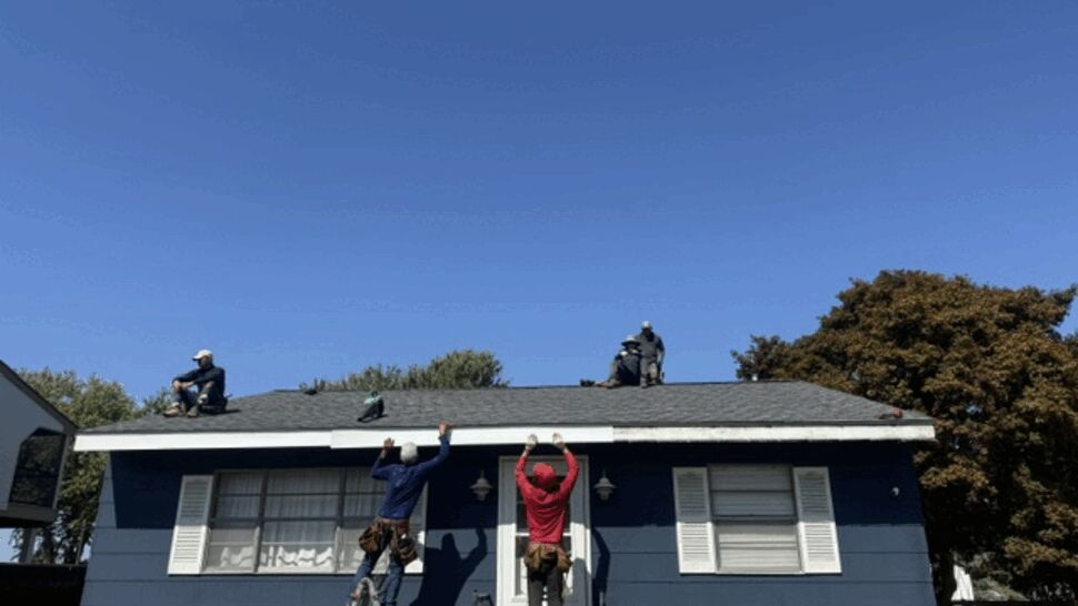 Roof crew working on shingle installation above front door