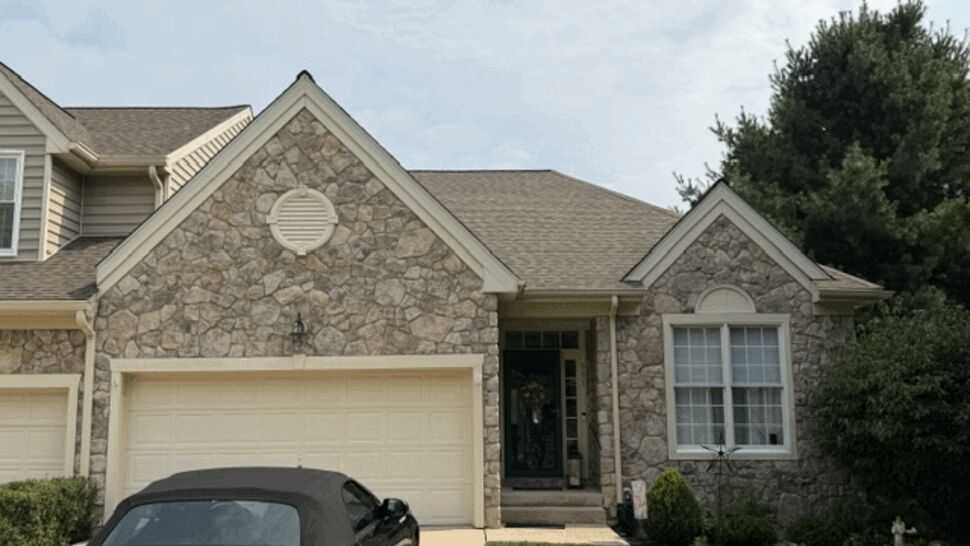 Front driveway with convertible and two-car garage beneath a brown roof.