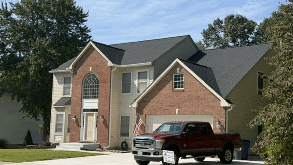Pickup truck parked in driveway of two-story house after roof work