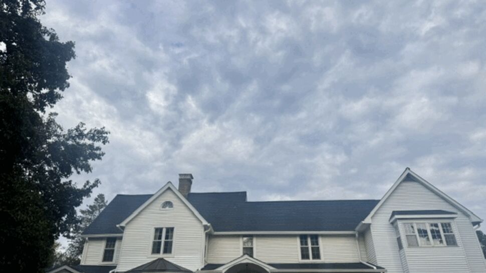 Large white home with dark roof and landscaped front yard