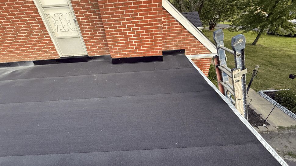Flat roof and chimney detail | Atlas Exteriors Flat roof section by chimney with ladder along edge.