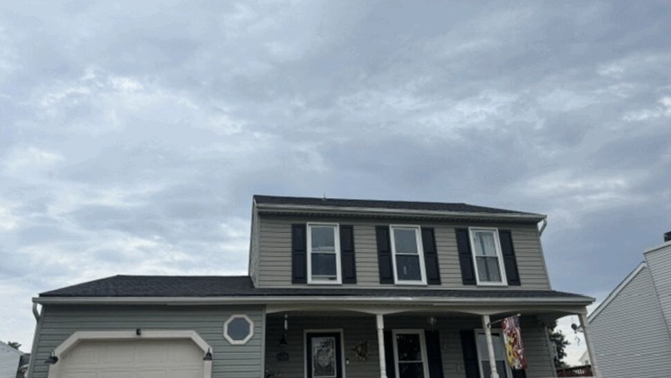 Front view of a two-story gray house with porch, white trim and garage.