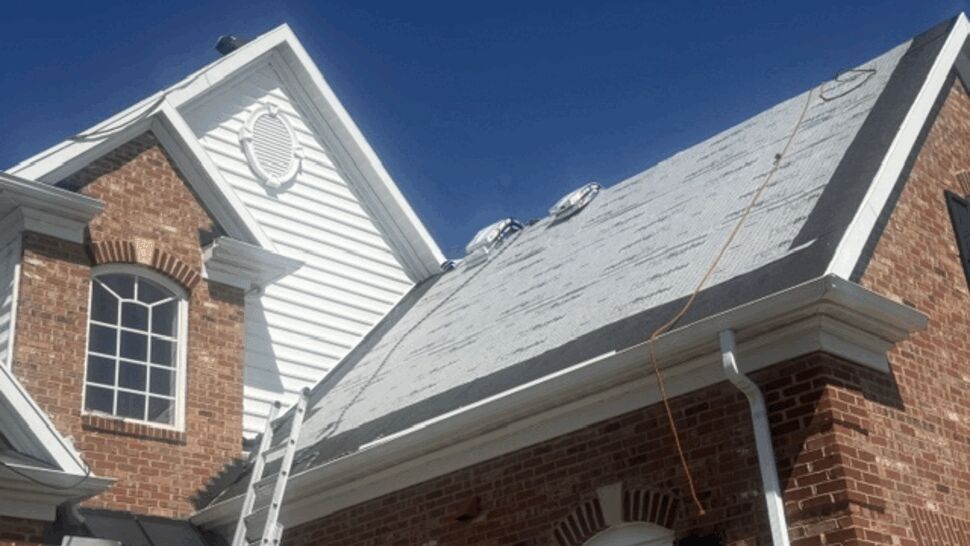 Front gable roof covered in underlayment with ladder propped up.