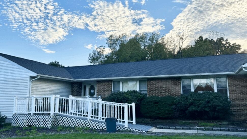 Completed Home Roofing Project | Atlas Exteriors Single-story brick and siding home with a dark shingle roof and white deck.