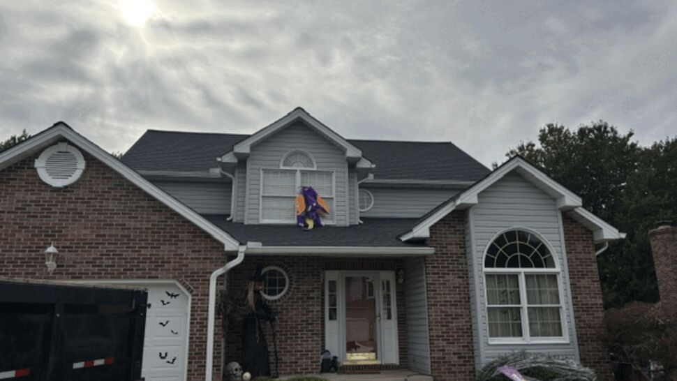 Front view of a brick and siding home undergoing roof work.