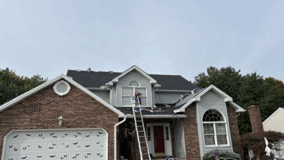 Crews replace the roof of a brick-front suburban home.