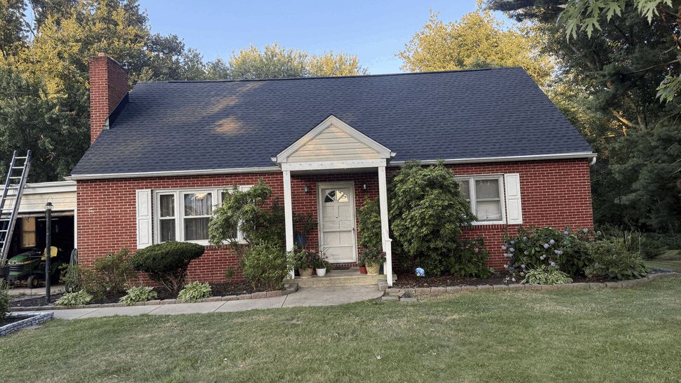 Front view of brick home with new roof | Atlas Exteriors Wide front view of brick home with dark roof and small porch.
