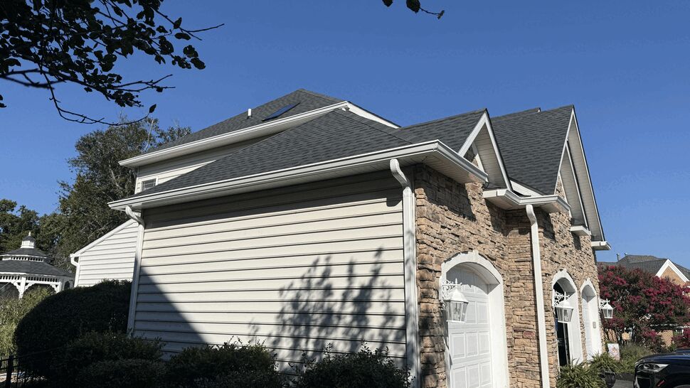 Side view of garage showing white gutters and downspouts with stone veneer.