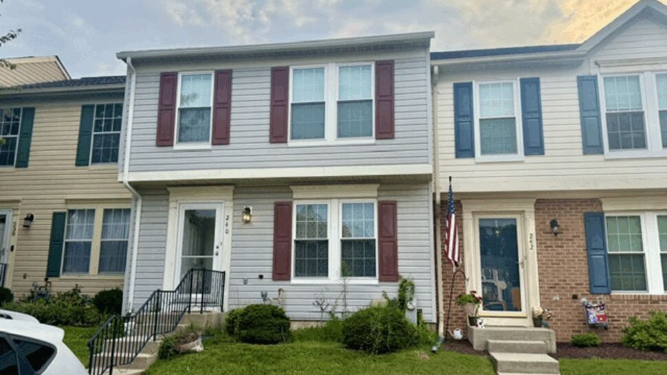 Front two-story gray townhome with burgundy shutters and vinyl siding