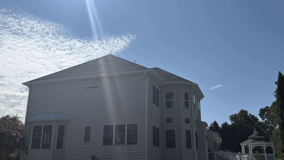 Two-story home with white siding and gutters under bright sun.