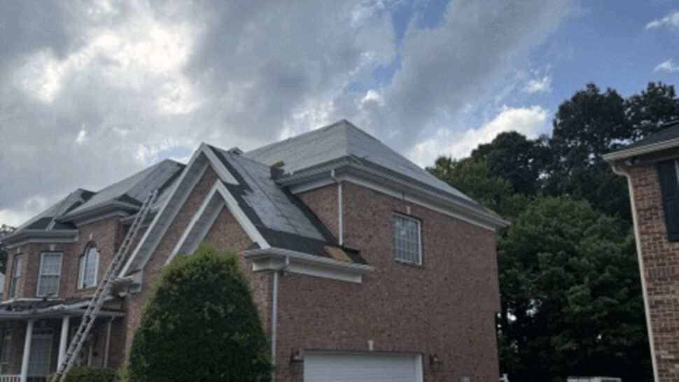Front corner of house with roofing underlayment exposed and ladder in place.