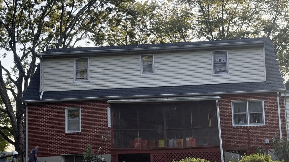 Rear brick house with upper siding | Atlas Exteriors Rear of brick house with white siding on upper level and screened porch.