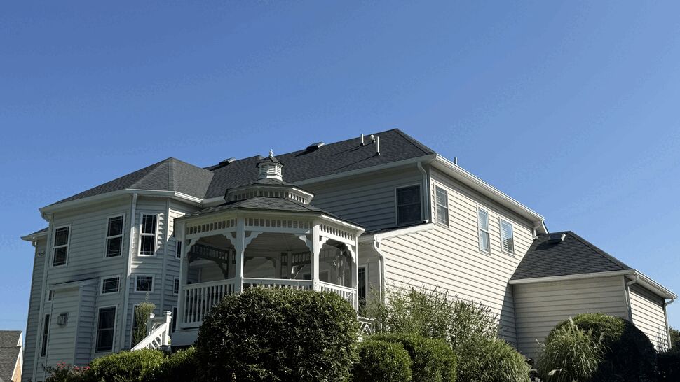 Rear elevation of a house with light-colored siding, gazebo, and manicured landscaping.
