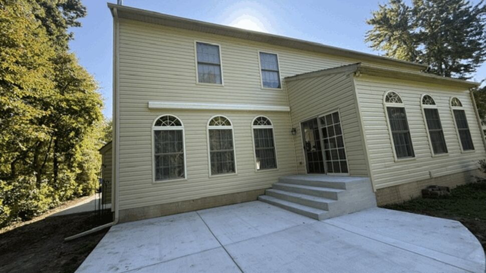 Rear patio with concrete slab steps and light yellow siding on the house