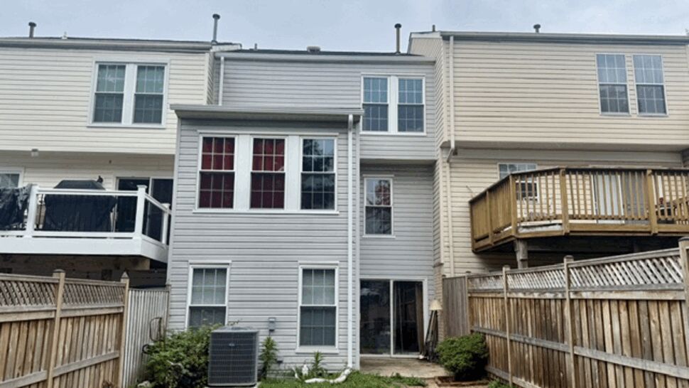 Rear of townhouse with fenced yard, deck and visible gutters and downspouts