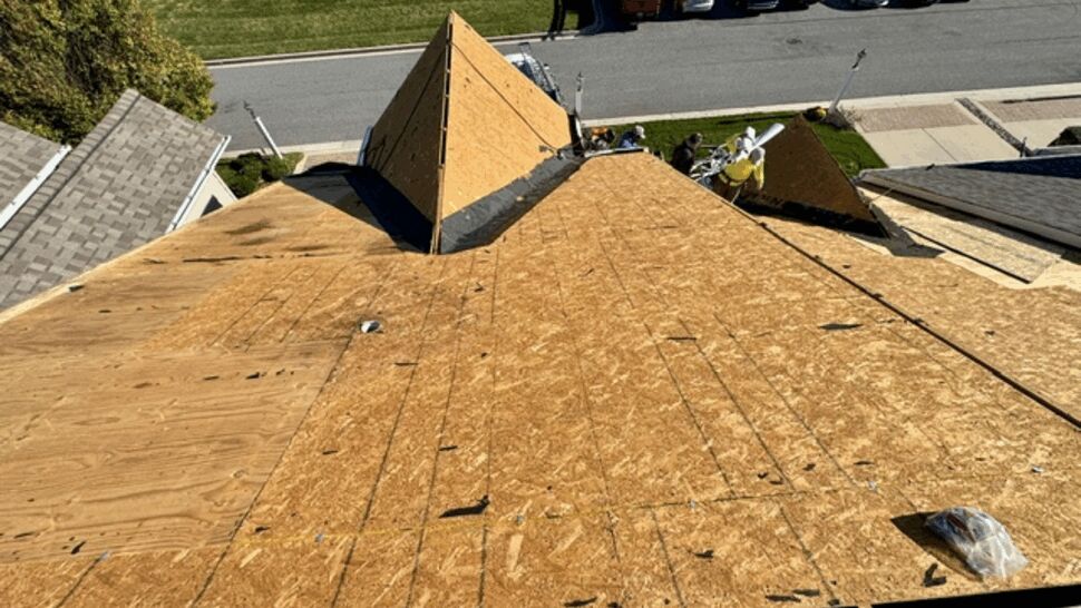 Roofers working on a home with exposed plywood roof decking