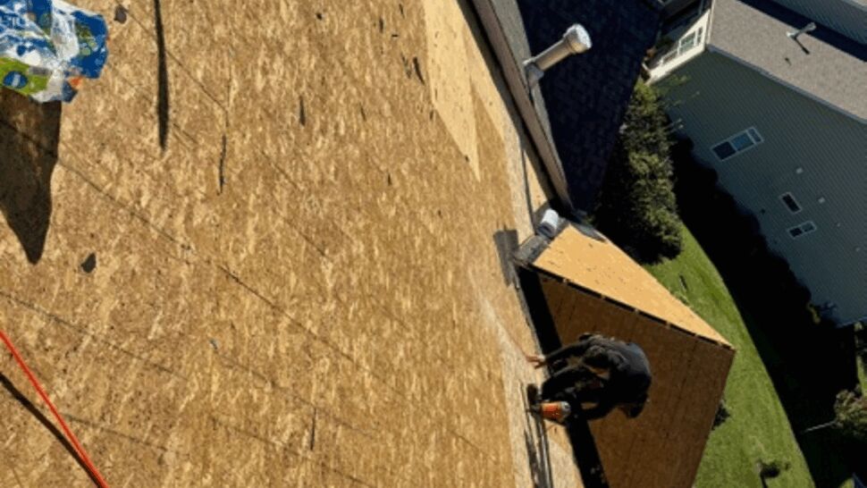 Exposed roof decking and roofing tools viewed from a steep roof
