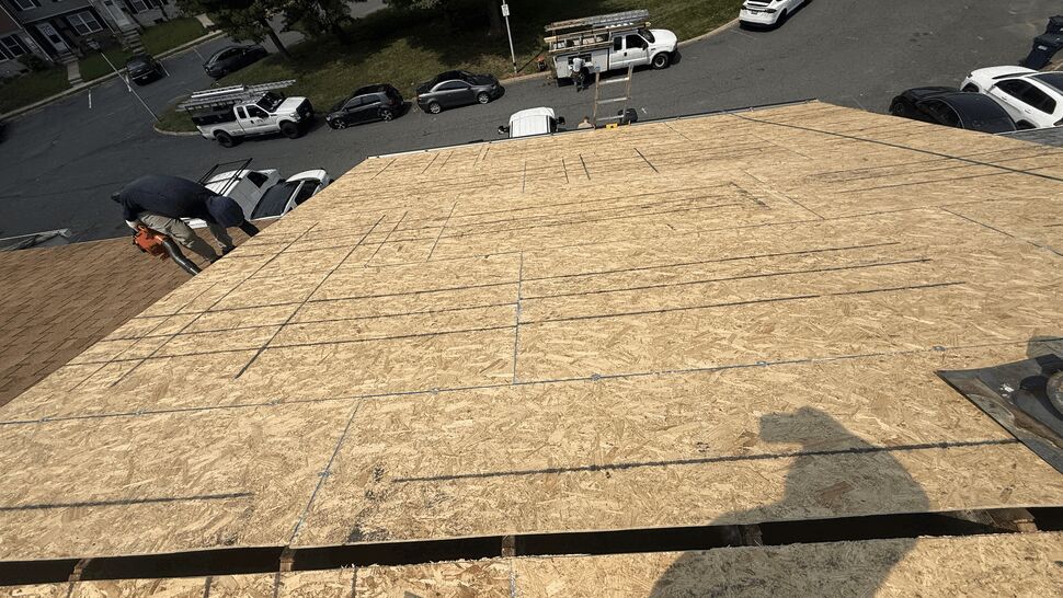 Wide view of newly installed roof decking with layout markings and crew at the far edge.