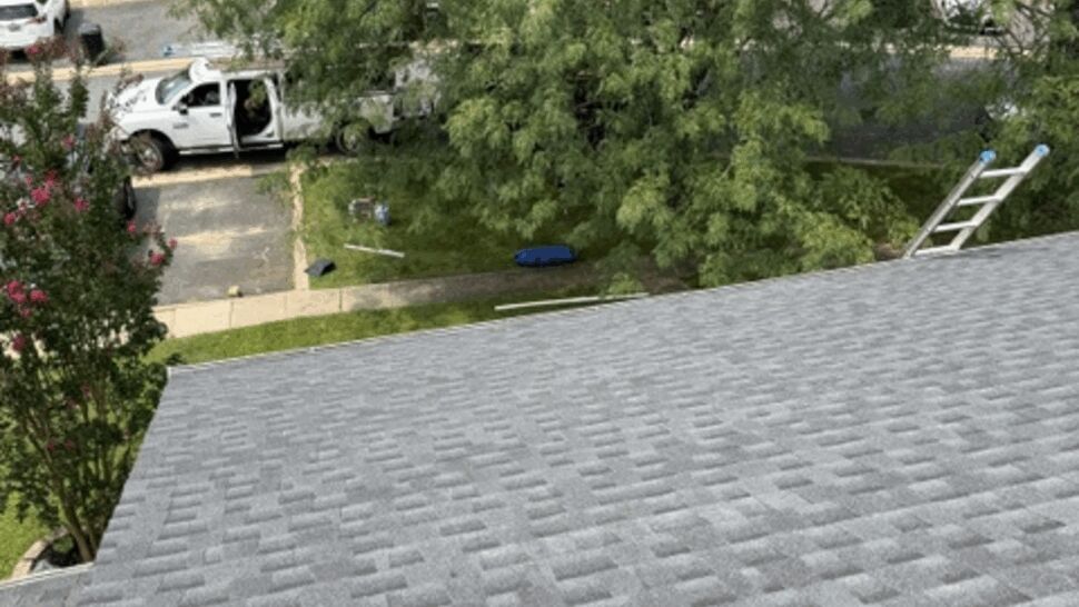 Looking over roof edge to street with parked work truck and ladder