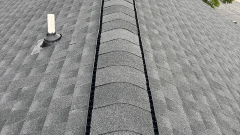 Close view of a ridge vent running along the peak of a gray shingle roof.