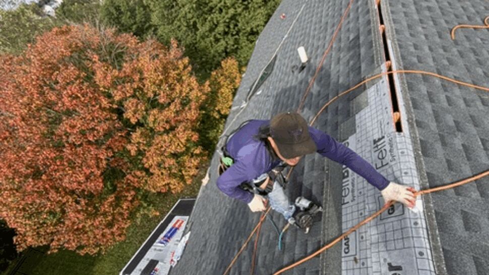Roofing crew installs shingles and underlayment on a sloped roof.