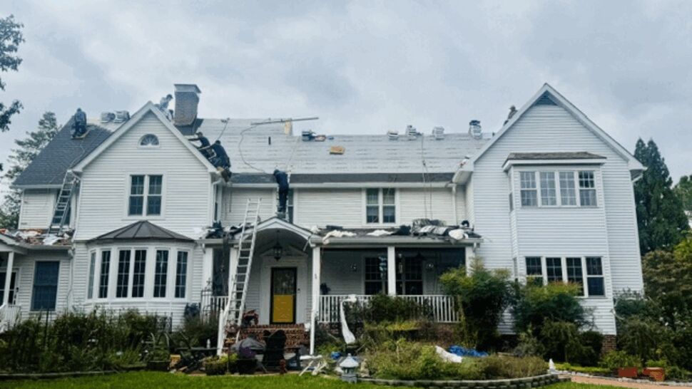 Roofing workers installing underlayment on a large home