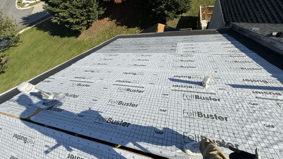 Roof deck covered with synthetic underlayment during installation.