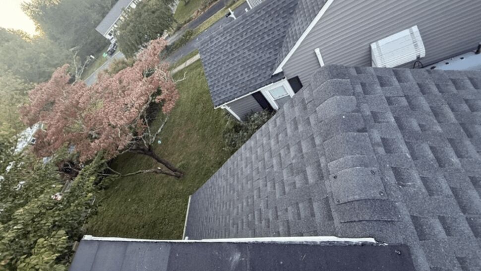 Close aerial view of gray shingles, roof valleys, and adjacent siding.