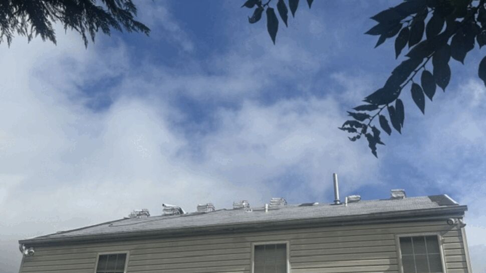 Low-angle view of roof with multiple vents beneath cloudy sky