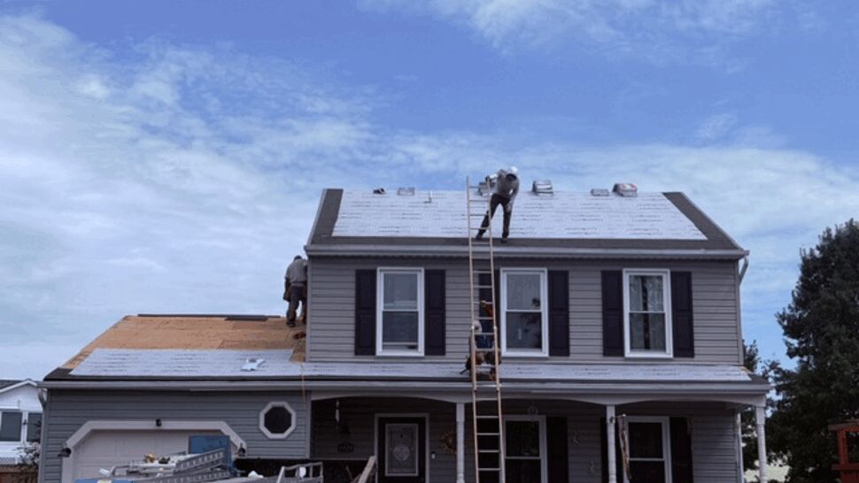Crew on roof installing underlayment and preparing for shingle installation.