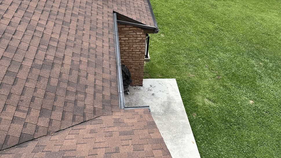 Aerial view of shingled roof and gutter along patio edge