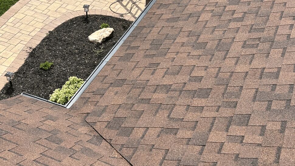 Close-up of asphalt shingles and roof valley near a concrete slab