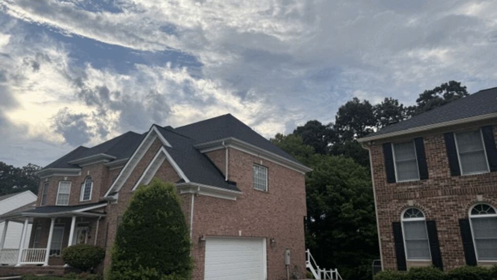 Side view of brick home with attached garage and dark roof.