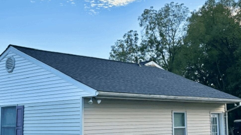 Side Elevation Roofing and Siding | Atlas Exteriors Side view of a white-sided home with a dark shingle roof and driveway.