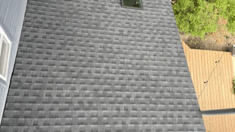 Section of new roof with two skylights set into gray shingles.