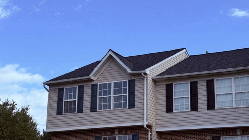 Townhome exterior with dark roof, light siding, and blue shutters.