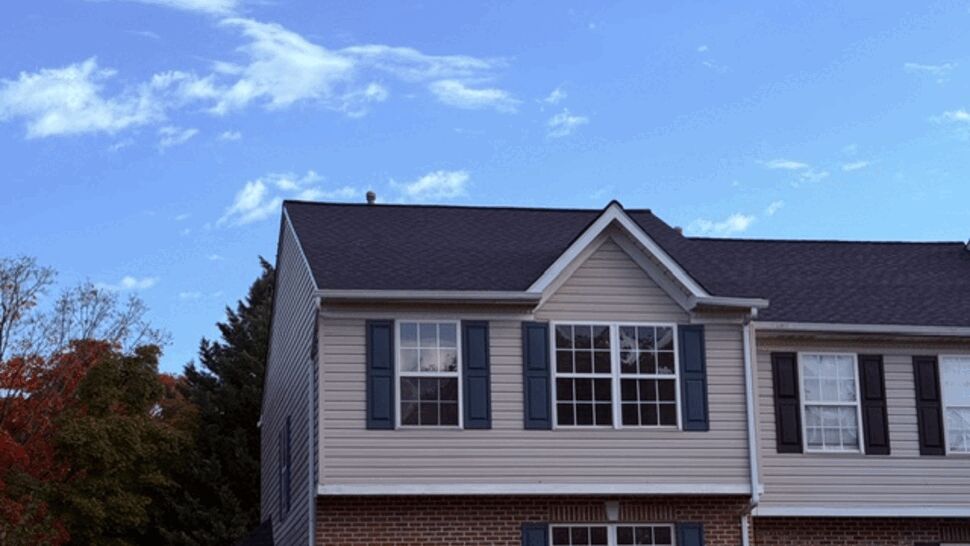 Front view of a townhome with gray siding and dark shingle roof.