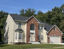 Angled side view of house showing dark roof and cream vinyl siding