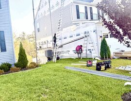 Home siding project with workers, tools, ladders, and materials on the lawn