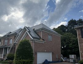 Front corner of house with roofing underlayment exposed and ladder in place.