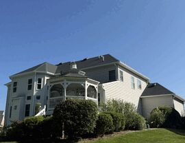 Rear elevation of a house with light-colored siding, gazebo, and manicured landscaping.