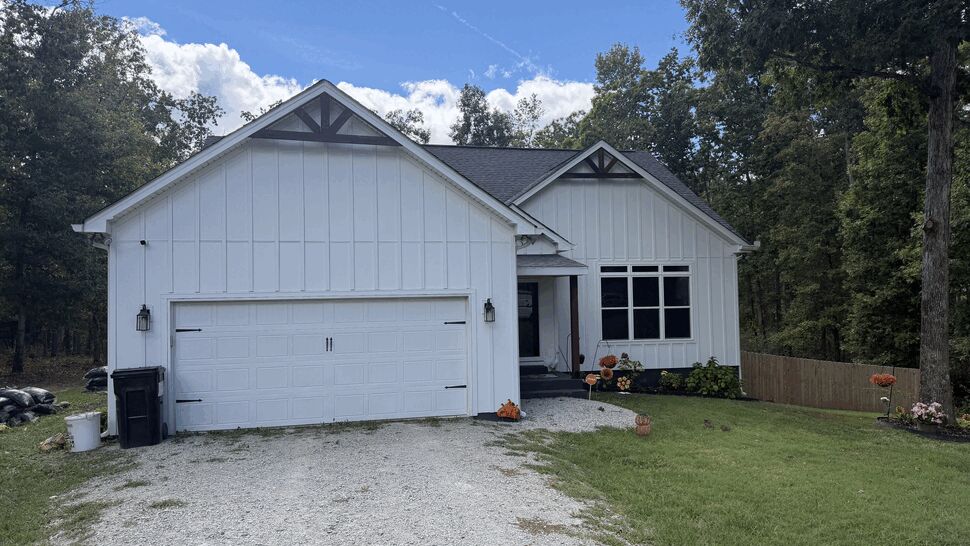 Front Home and Garage Exterior | DominionX White home front with double garage, dark roof, windows, and gravel driveway.