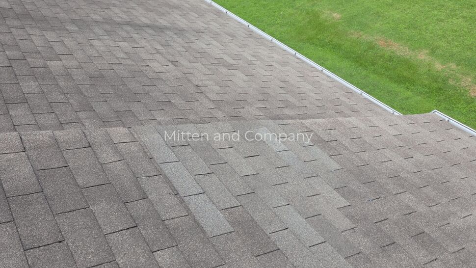 Aerial shingle roof slope inspection | Mitten & Company Aerial view of sloped shingle roof showing wear and algae streaks near the gutter