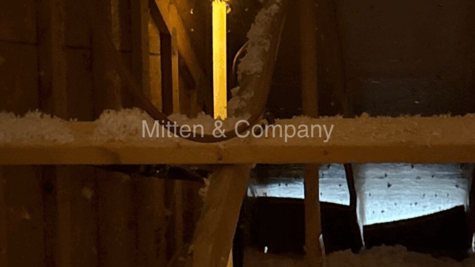 Attic interior with loose-fill insulation and a vertical light near vents