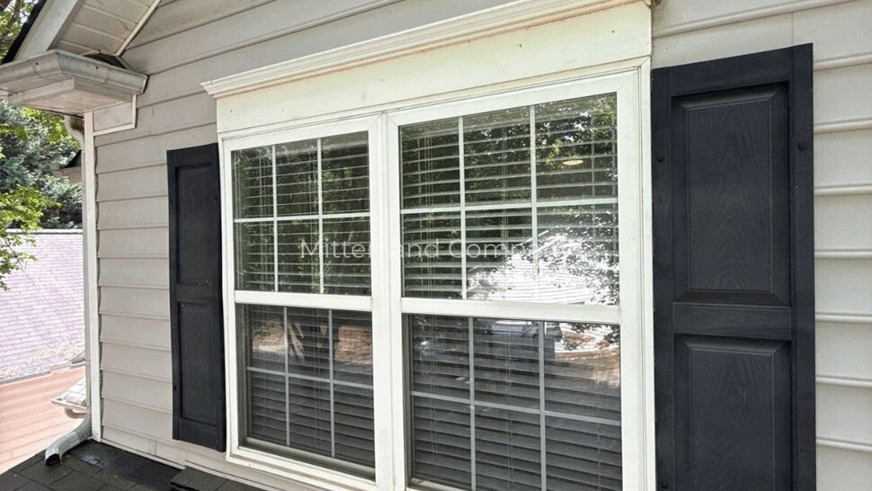 Bay Window Siding and Trim Detail | Mitten & Company Bay window with white trim, gray siding, and black shutters